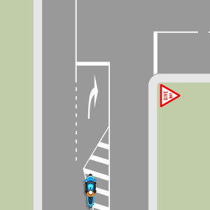 A blue motorcycle riding over the white diagonal lines of a right-turn bay.