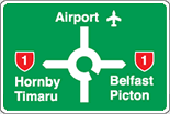 Green information highway sign showing directions to airport using a roundabout symbol. To the left of the roundabout is Hornby or Timaru with a red state highway 1 symbol. To the right is Belfast or Picton with a red state highway 1 symbol.
