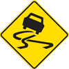 Permanent warning traffic sign showing a car icon tilted on a road implying slippery surface on a yellow background